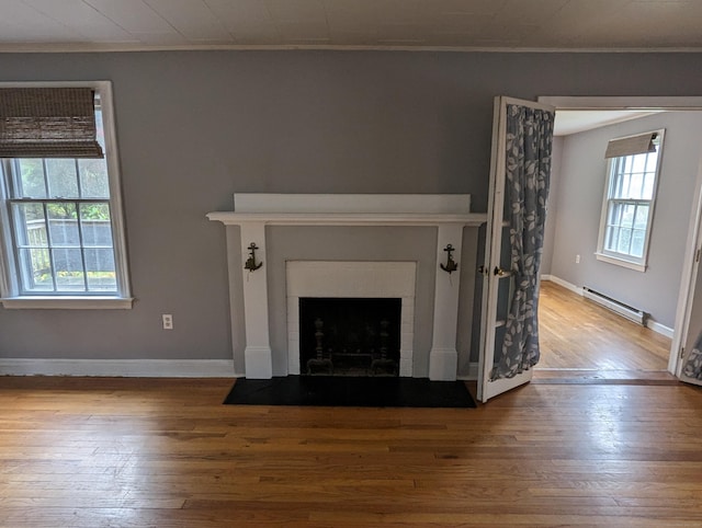 unfurnished living room with a baseboard radiator, crown molding, and light hardwood / wood-style flooring