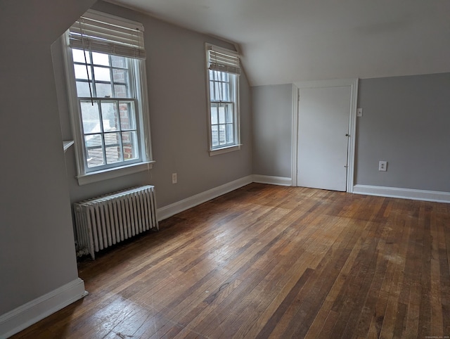 bonus room featuring dark wood-type flooring, lofted ceiling, and radiator