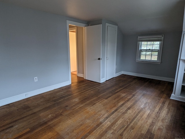 unfurnished bedroom featuring vaulted ceiling and dark hardwood / wood-style floors