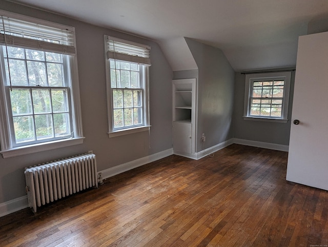 additional living space with radiator, vaulted ceiling, and dark hardwood / wood-style floors