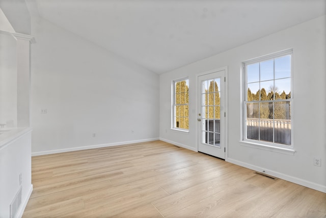 spare room with vaulted ceiling, light hardwood / wood-style floors, and decorative columns