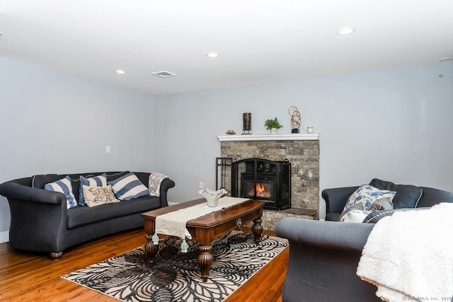 living room with wood-type flooring and a stone fireplace