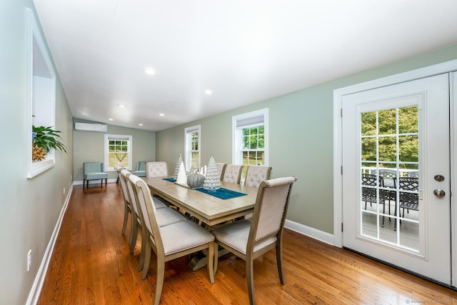 dining room with lofted ceiling, a wall mounted air conditioner, and wood-type flooring