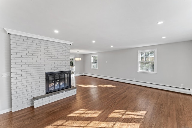 unfurnished living room with wood-type flooring, a brick fireplace, plenty of natural light, and baseboard heating