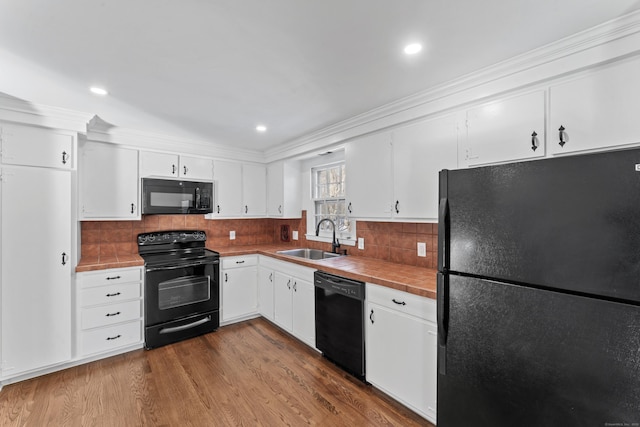 kitchen with white cabinetry, tile countertops, sink, and black appliances