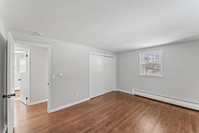 spare room featuring baseboard heating and hardwood / wood-style flooring