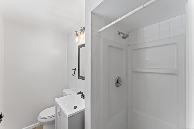 bathroom with vanity, tiled shower, and toilet