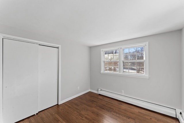 unfurnished bedroom with dark hardwood / wood-style flooring, baseboard heating, and a closet