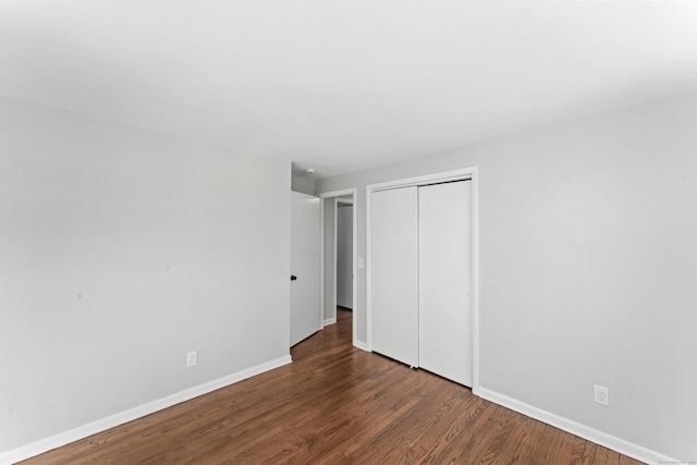 unfurnished bedroom with dark hardwood / wood-style flooring and a closet