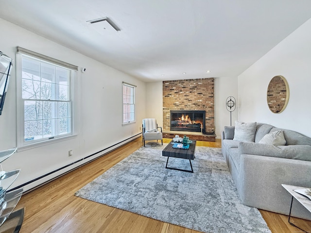 living room featuring a baseboard radiator, a fireplace, and light hardwood / wood-style flooring