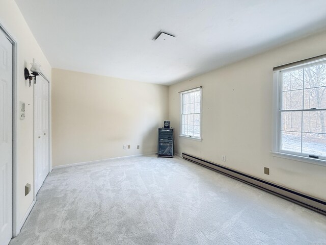 unfurnished bedroom featuring light colored carpet and baseboard heating