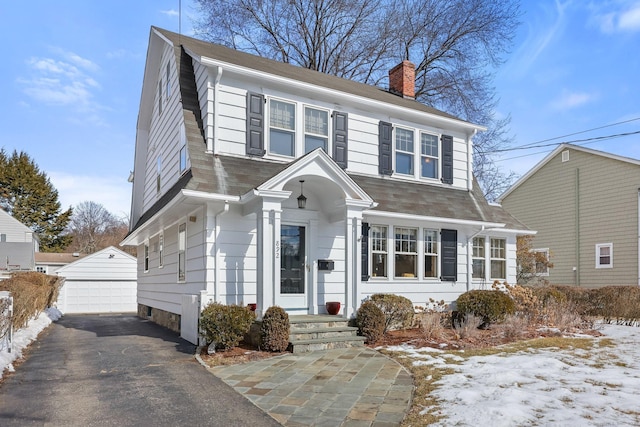 dutch colonial with a chimney, a detached garage, and an outdoor structure