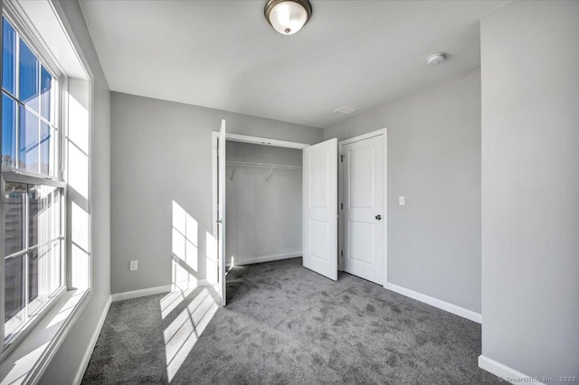 unfurnished bedroom featuring dark carpet and a closet