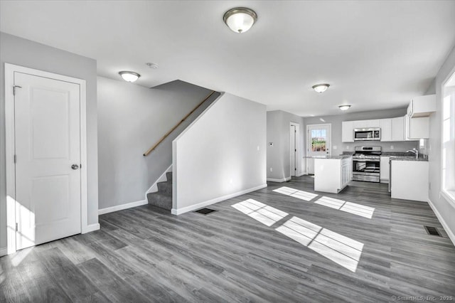 kitchen with a kitchen island, white cabinetry, sink, stainless steel appliances, and dark wood-type flooring