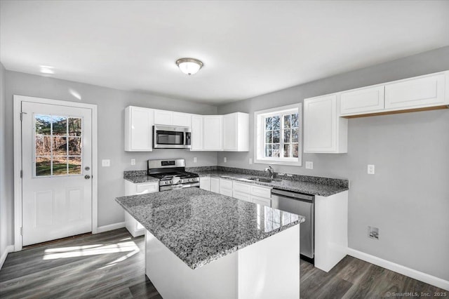 kitchen with appliances with stainless steel finishes, a center island, a wealth of natural light, and white cabinets