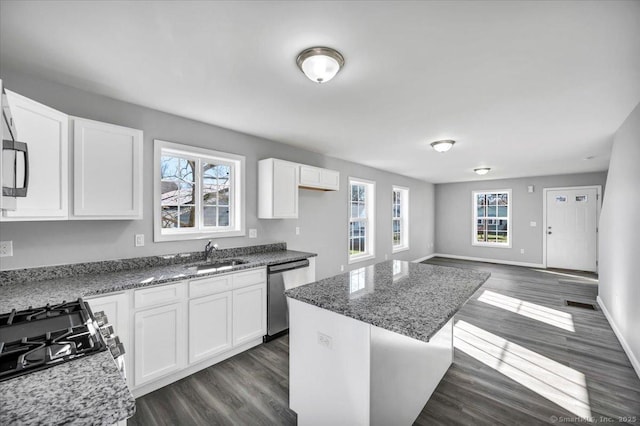 kitchen with sink, a center island, dark stone countertops, stainless steel appliances, and white cabinets