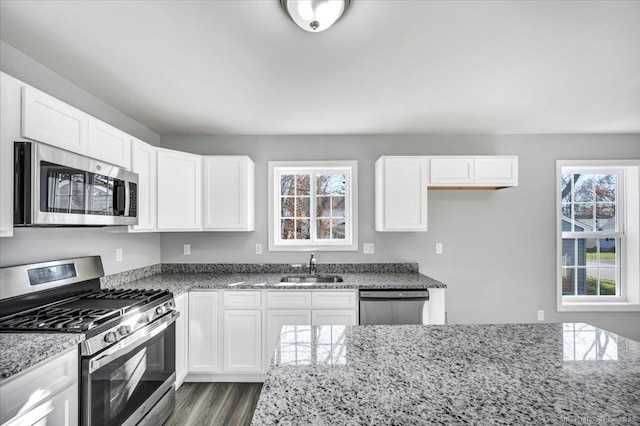 kitchen with sink, white cabinetry, stainless steel appliances, dark hardwood / wood-style floors, and stone countertops