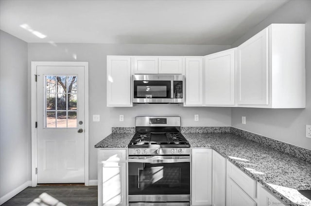 kitchen featuring stainless steel appliances, white cabinetry, light stone countertops, and dark wood-type flooring