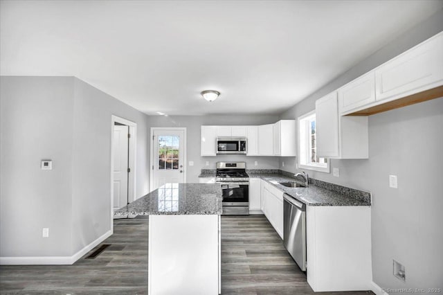 kitchen with a kitchen island, appliances with stainless steel finishes, plenty of natural light, and white cabinets