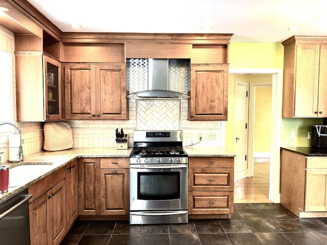 kitchen with sink, light stone counters, wall chimney range hood, stainless steel appliances, and backsplash