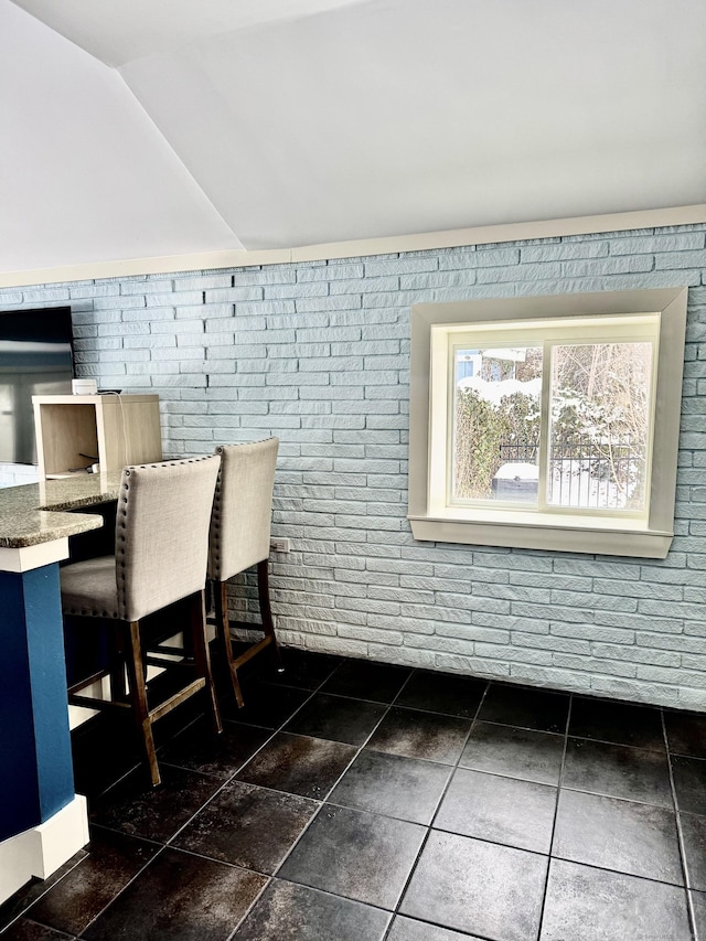 dining area with brick wall and lofted ceiling