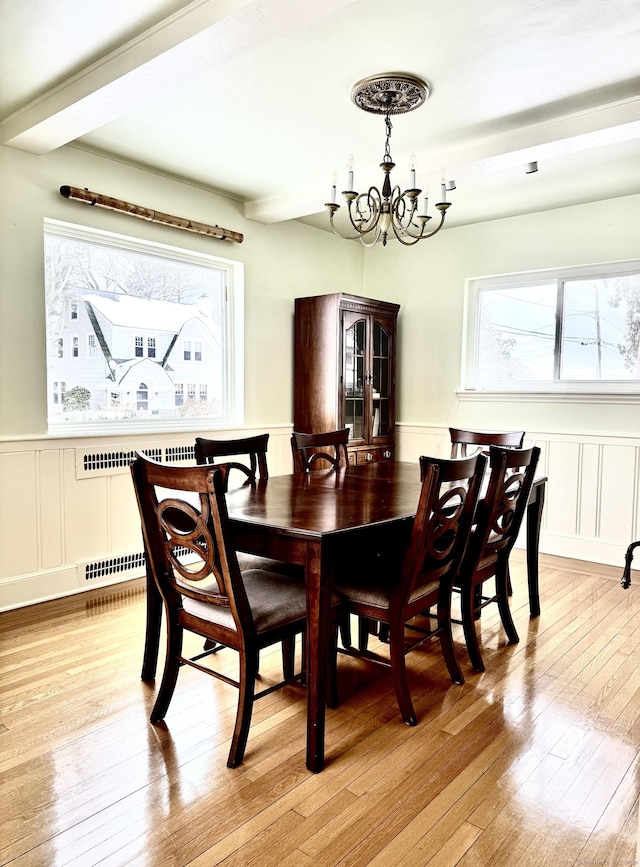 dining area featuring beamed ceiling, a healthy amount of sunlight, a chandelier, and light wood-type flooring