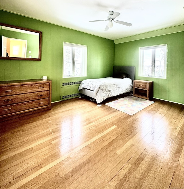 bedroom with light hardwood / wood-style flooring, radiator heating unit, and ceiling fan