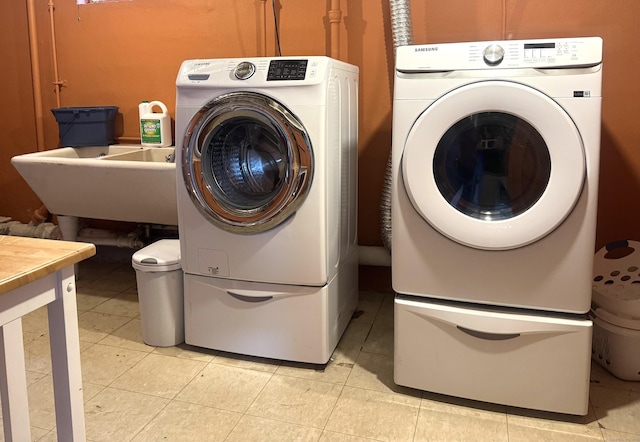 washroom featuring light tile patterned flooring, sink, and washing machine and clothes dryer