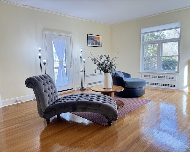 sitting room featuring hardwood / wood-style flooring, crown molding, a healthy amount of sunlight, and baseboard heating