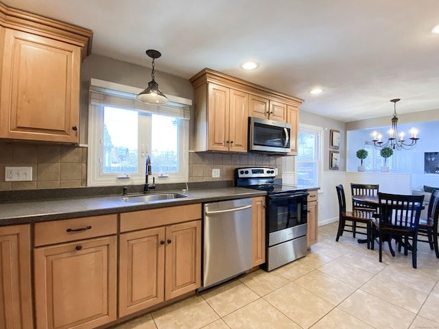 kitchen with light tile patterned flooring, stainless steel appliances, decorative light fixtures, and sink