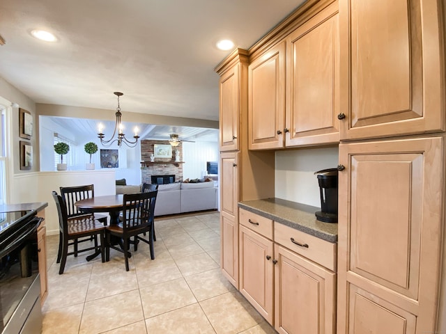 kitchen featuring light tile patterned floors, hanging light fixtures, electric range, a large fireplace, and light brown cabinets