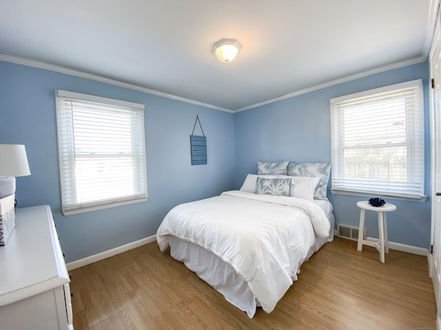 bedroom with crown molding and light hardwood / wood-style floors