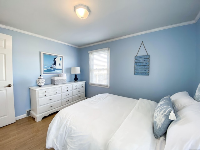 bedroom featuring ornamental molding and light hardwood / wood-style floors