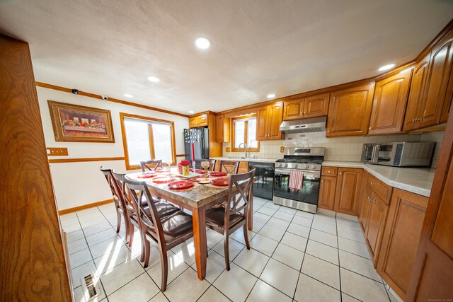 kitchen featuring light tile patterned flooring, sink, black appliances, ornamental molding, and backsplash