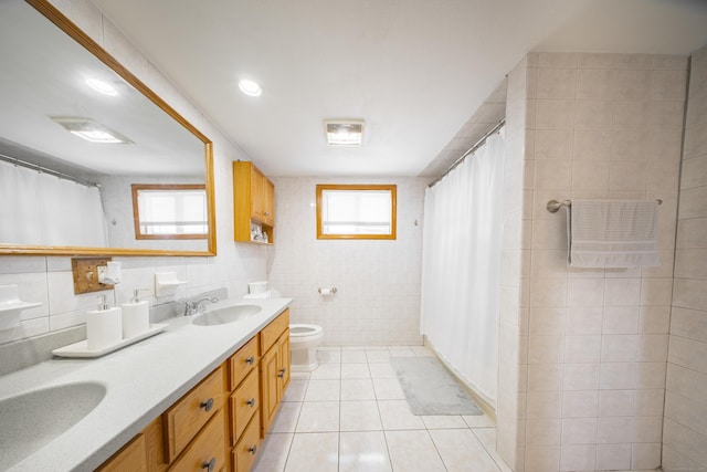 bathroom with a healthy amount of sunlight, tile patterned flooring, vanity, and tile walls