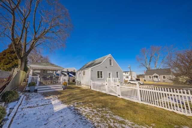 snow covered house with a yard, a gazebo, central AC, and a deck