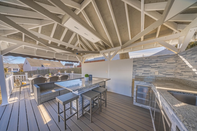 wooden deck with outdoor lounge area, exterior bar, and area for grilling