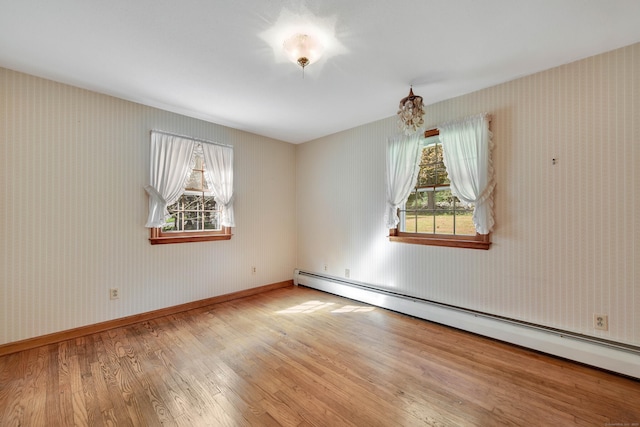 unfurnished room featuring a baseboard heating unit and light hardwood / wood-style floors