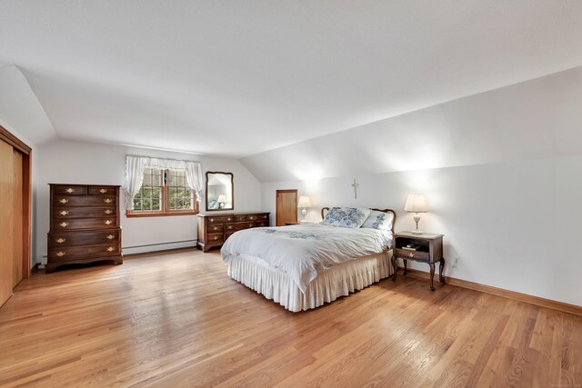 bedroom with baseboard heating, vaulted ceiling, and light hardwood / wood-style flooring