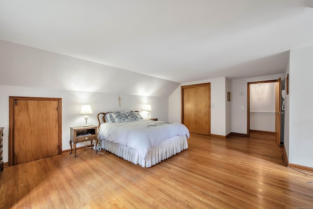 bedroom featuring a closet, lofted ceiling, and light hardwood / wood-style flooring