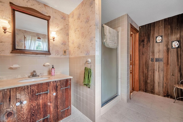 bathroom featuring vanity, a shower with shower door, tile patterned flooring, and tile walls