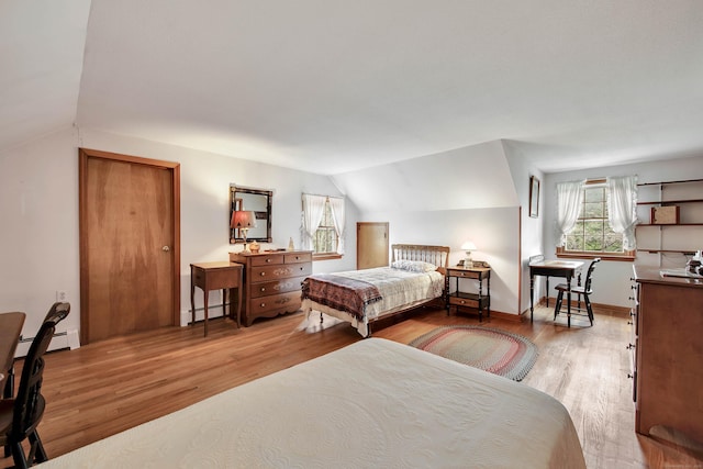 bedroom with lofted ceiling, light hardwood / wood-style flooring, and baseboard heating