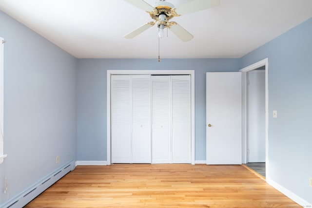 unfurnished bedroom featuring baseboard heating, ceiling fan, a closet, and light wood-type flooring