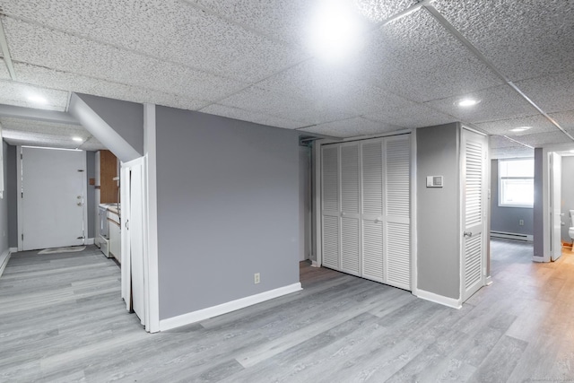 interior space with a baseboard radiator, a paneled ceiling, and light hardwood / wood-style flooring