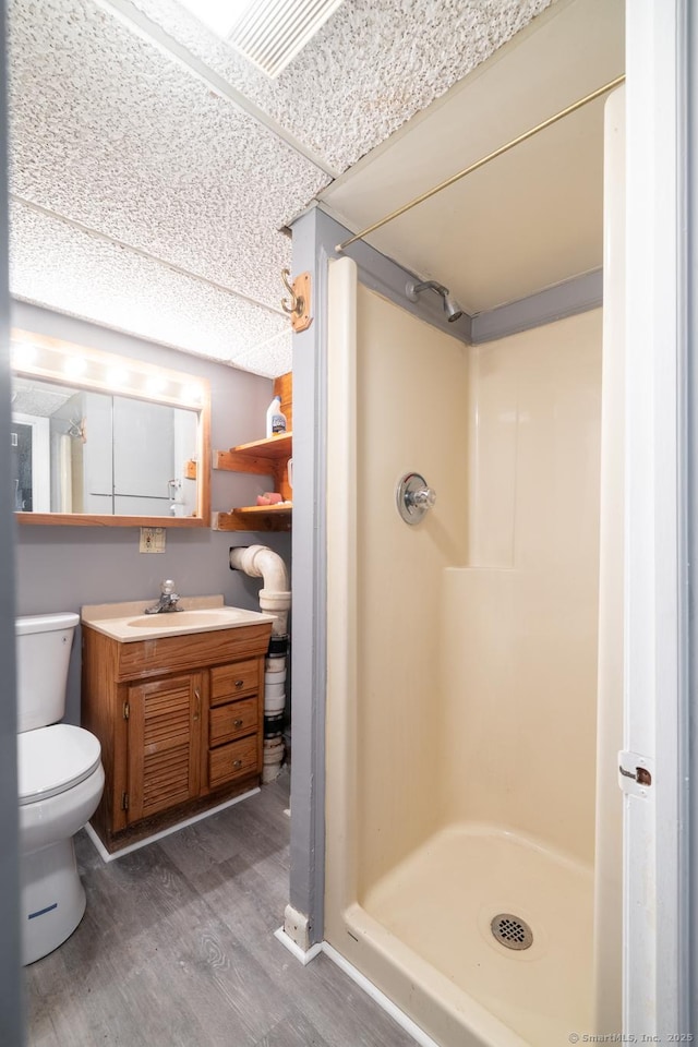 bathroom featuring hardwood / wood-style flooring, a shower, vanity, and toilet