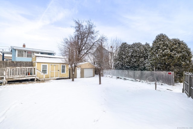 yard covered in snow featuring an outbuilding and a garage