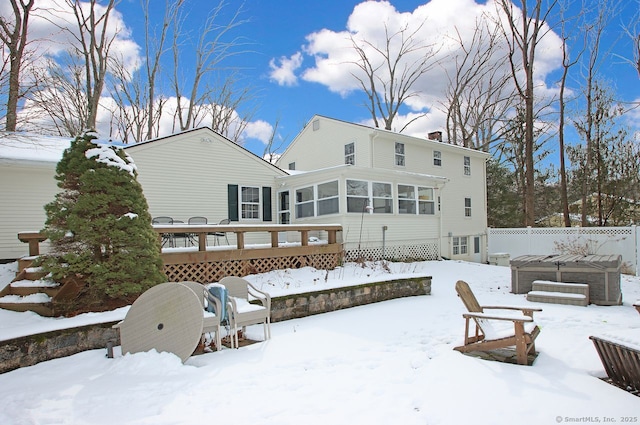 snow covered rear of property featuring a wooden deck and a sunroom