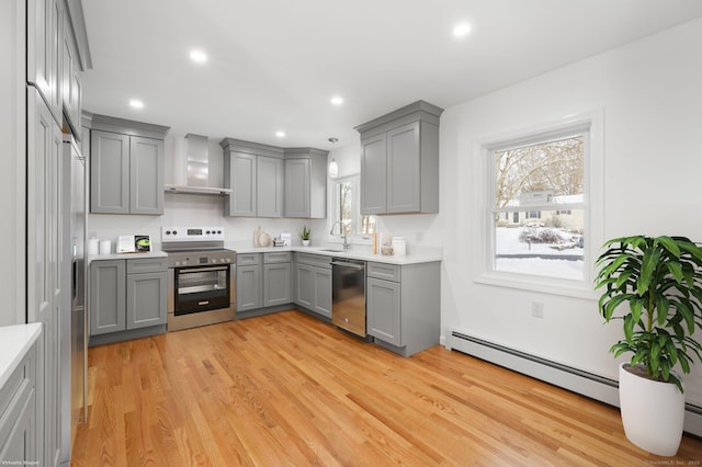 kitchen with pendant lighting, gray cabinets, stainless steel appliances, and wall chimney exhaust hood