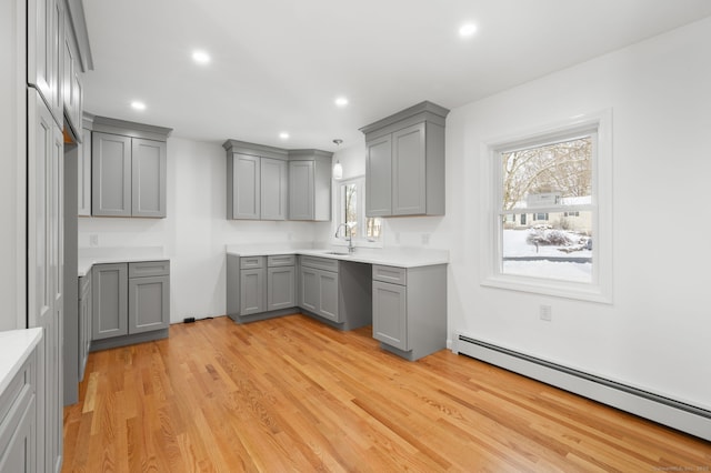 kitchen featuring sink, gray cabinets, pendant lighting, light hardwood / wood-style floors, and a baseboard heating unit