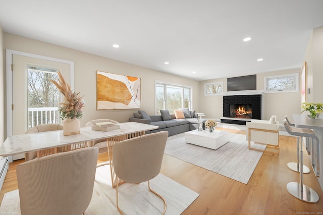 living room featuring a baseboard heating unit, a fireplace, and light wood-type flooring